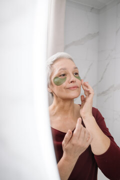 A woman applies eye patches