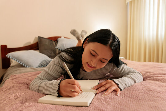 Woman Journaling While Lying on Bed at Home
