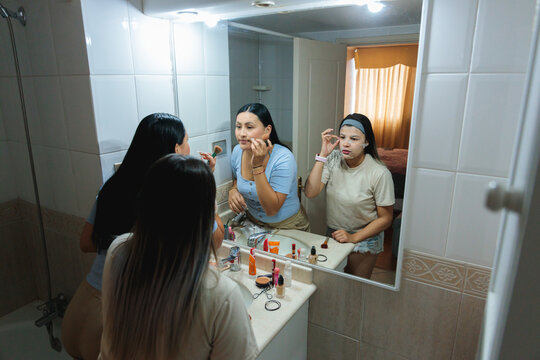 Two Latina Women Sharing Beauty Routine in Bathroom