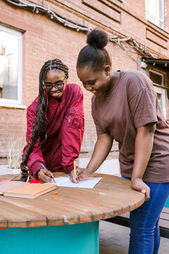 Friends study together outside at a table
