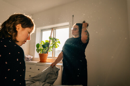 Two People Prepare a Room With Sunlight and Plants in the Morning