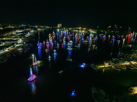 Aerial view of numerous boats decorated with vibrant colorful lights during a night parade in a marina Yucatan, Mexico.