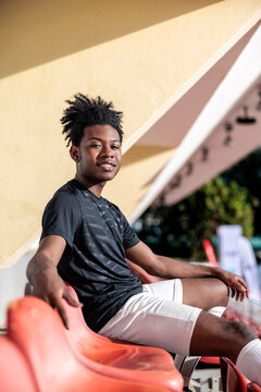 Happy athlete sits in sunny stadium seat