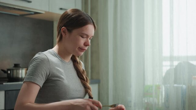 Pregnant white woman preparing breakfast at kitchen counter, chopping ingredients and assembling plate, braid over shoulder, bright window light, focused expression, prenatal nutrition and mindful