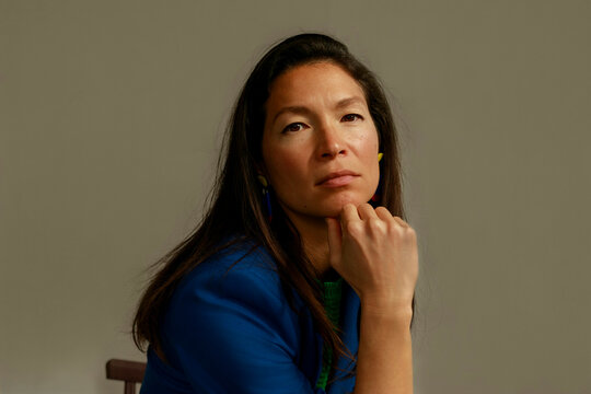 Woman Resting Chin on Hand With Thoughtful Expression Indoors