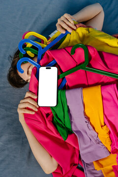 Smartphone Mockup Lying Among Bright Clothes on Hangers 