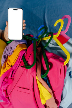Smartphone with Blank Screen Among Colorful Clothes on Hangers