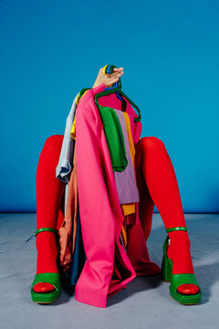 Seated Figure Hidden Behind Colorful Clothes on Hangers in Studio