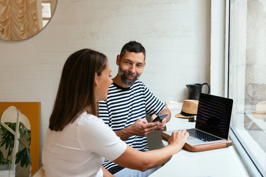Side view of colleagues working on a laptop in a modern coffe shop
