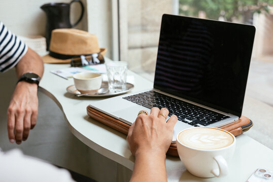 Two Unrecognizable People Working On A Laptop In A Modern Coffee