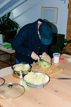 Man chopping cabbage in his kitchen while preparing homemade kimchi