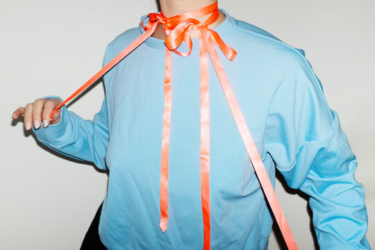 Person wearing a fashion style blue shirt with pink silk ribbon bow 