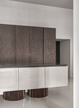 Modern kitchen interior with sculptural island and dark wood cabinetry