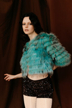 Woman in turquoise faux fur jacket and sequin shorts