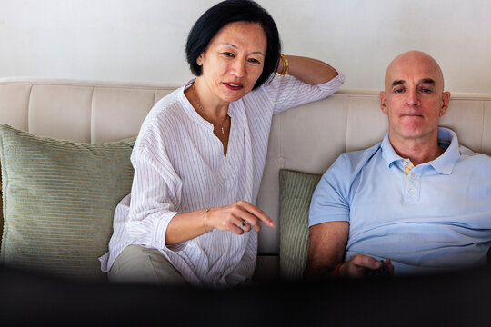 Couple relaxing on a couch, woman pointing forward.