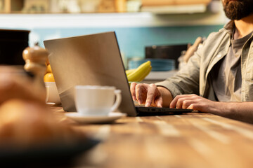 Fototapeta premium Laptop close up, typing data on keyboard, teleworking at home, rustic kitchen environment, solving daily tasks. Relaxed posture, modern interior design, flexible work and productivity, lifestyle.