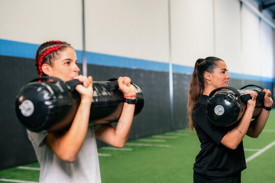 Women training in gym using power bags