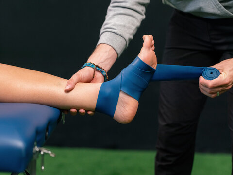 Physiotherapist applying floss band on athlete leg