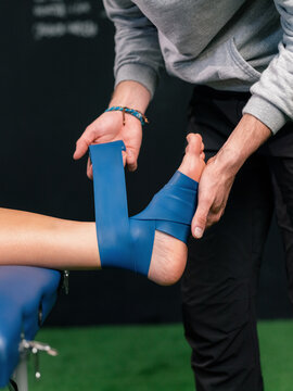 Therapist Wraps Ankle for Support After Injury During Recovery Session