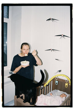 Woman eats while baby sleeps in crib