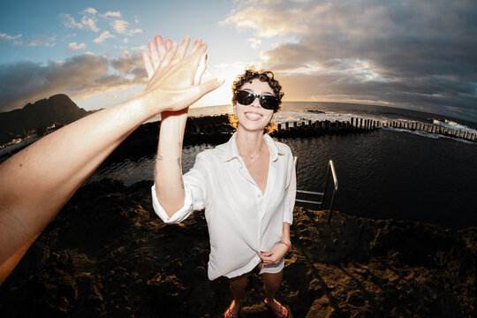 Traveling partners high-fiving at sunset by natural pools