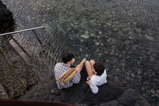Two individuals relaxing at natural volcanic swimming pools