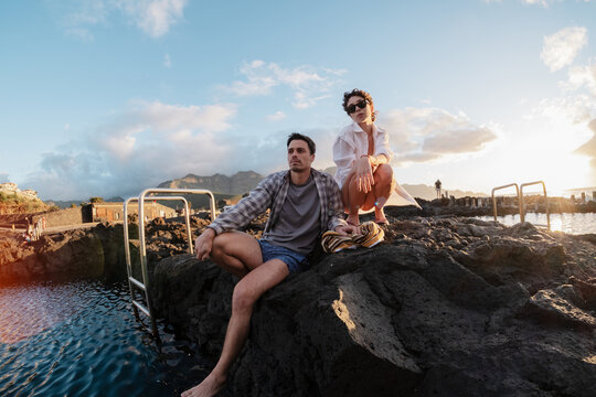 Partners enjoying natural pools at sunset on vacation