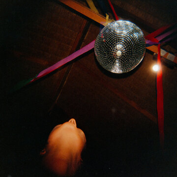 Disco Ball Hanging Above Person With Colorful Ribbons in a Party
