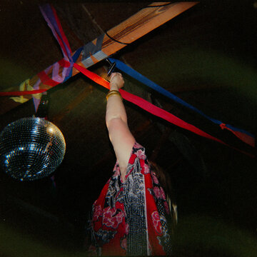 Dancer reaching up to Disco Ball at party setting