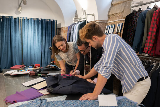 Client discussing sketch with dressmaker and assistant