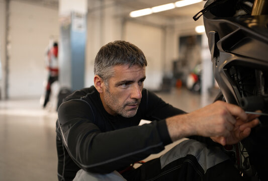 Man repairing motorcycle on garage floor
