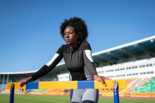 African American sportswoman resting near hurdle