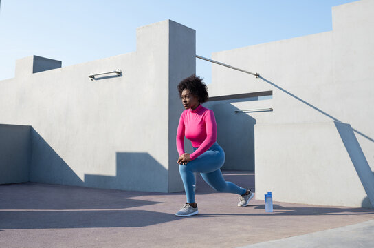 Black sportswoman lunging on sunny day