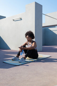 Black sportswoman browsing smartphone during break