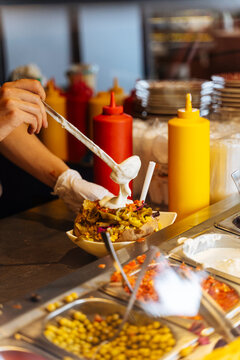 Serving sauce on loaded baked potato at a fast-casual restaurant