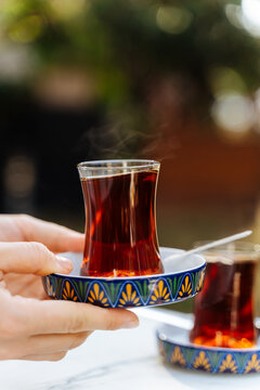 Hand holding a glass of hot tea