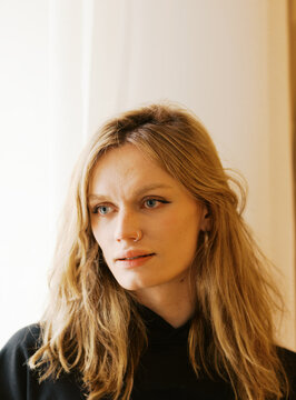 Woman With Long Hair at Window in Indoor Setting During Daylight