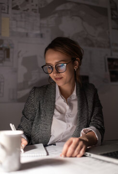 Glad businesswoman making notes at night
