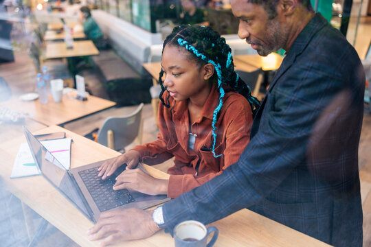 Mentoring session, Woman types on laptop with man looking on.