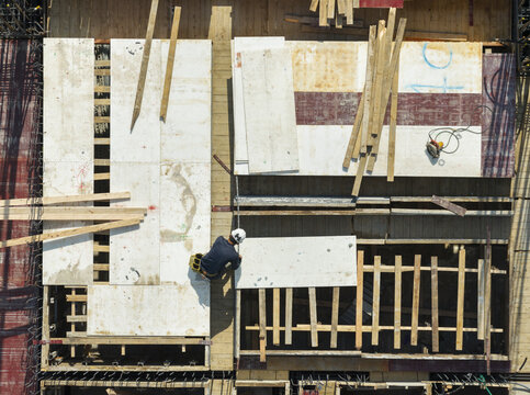 Aerial view of building construction and formwork with a worker installing wooden panels on a site in New Taipei, Taiwan.