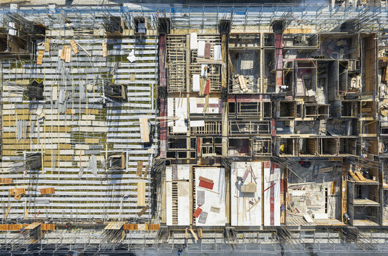 Aerial view of a building construction site showing formwork, scaffolding, and steel rebar with workers on the structure in New Taipei, Taiwan.