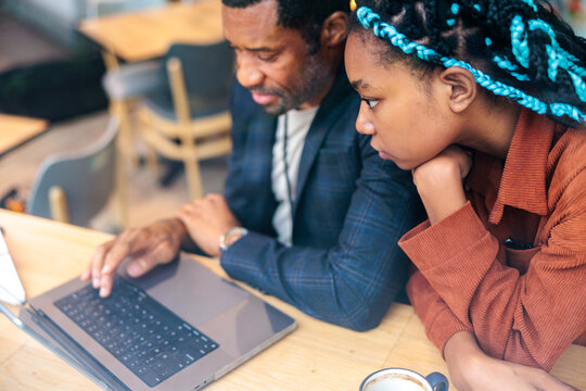Father and daughter working together on a laptop.