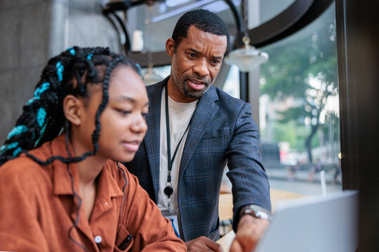 Mentoring, Man helps young woman with laptop work.