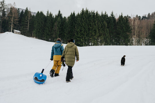 Family members pulling sled across snowy hillside
