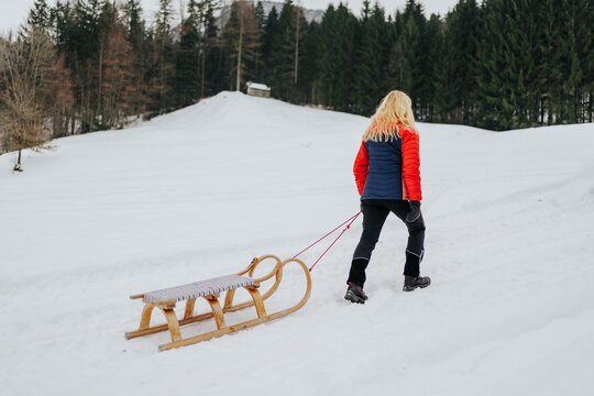 grandmother pulling traditional wooden sled in winter countrysid