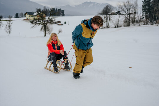 child pulling sled with happy grandmother