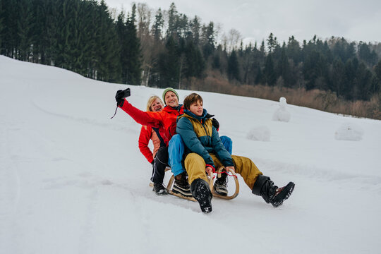 family riding sled together downhill in winter