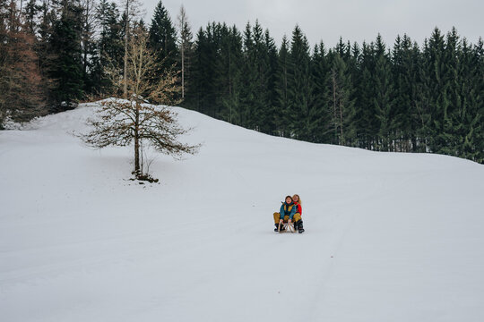 grandmother and grandson sliding gently on sled in snow