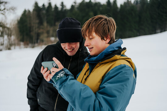 brothers sharing moment while checking phone outdoors
