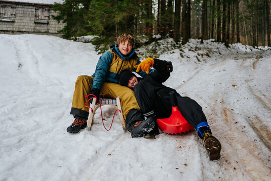 two brothers having fun on sled after winter play